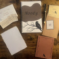 Writer's Corner — Autumn 2026, flat lay featuring the Moody raven notebook, journal prompts, pen, archive card, gold-edged deckled paper, and story insert.